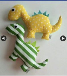 two stuffed dinosaurs sitting next to each other on top of a white table with green and white stripes