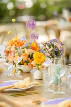 the table is set with colorful flowers and wine glasses