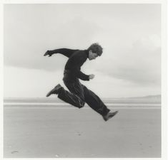 a man is running on the beach with his feet in the air as he jumps