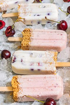 three popsicles on ice with cherries and crumbs next to each other