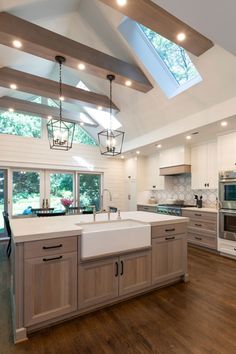 a large kitchen with wooden floors and skylights above the sink, windows on both sides