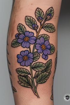 a tattoo with blue flowers and leaves on the leg, done by an expert in body art