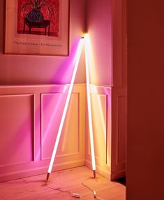 a pink light shines brightly on the floor in front of a wall with a painting