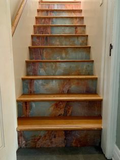 a set of wooden stairs leading up to an open door in a home with marbled steps