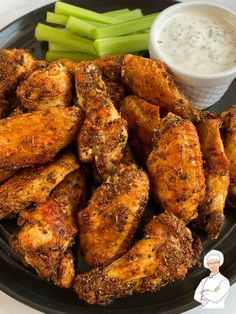 chicken wings and celery sticks on a plate with ranch dip in the background