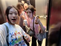 three girls are standing on an escalator and one girl is holding a cell phone