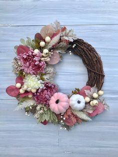 a wreath with flowers and leaves on a blue wooden background is hanging on the wall