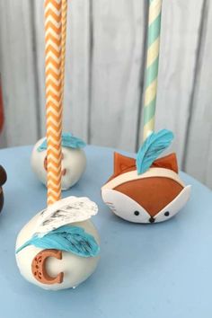 cake pops with frosting and decorations on top of a blue table next to two candles