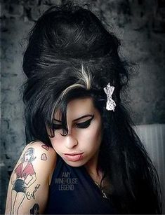 a woman with long black hair and tattoos on her arm