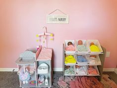 two doll houses with clothes and toys on the floor in front of a pink wall