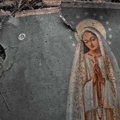 an image of the virgin mary painted on a concrete wall with peeling paint and debris around it