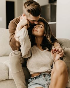 a man sitting on top of a couch next to a woman who is kissing her forehead