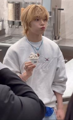 a young man eating an ice cream cone while standing in front of a kitchen counter