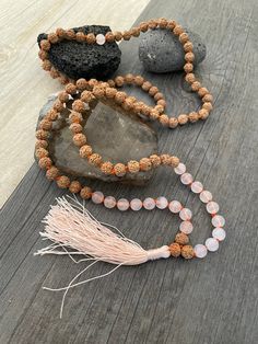 A most have addition to your Mala Necklace collection. A knotted mala with a mix of rose quartz beads and Rudraksha beads with a light pink tassel at the bottom. A stylish necklace that will also keep you grounded. Use it as a necklace, as a bracelet, even as a decor item in your room, or praying/ meditating area. The mala is 47cm- 18.5 inch drop length (without the tassel) The bottom tassel is 7.5cm- 3 inch long. The perfect gift for your loved ones. ⚡️Join Akashi's VIP list for early bird disc Pink Spiritual Crystal Necklace For Meditation, Rose Quartz Necklace With Gemstone Beads For Meditation, Spiritual Hand Knotted Mala As Gift, Adjustable Bohemian Rose Quartz Beaded Necklace, Rose Quartz 108 Beads Jewelry For Meditation, Spiritual Rose Quartz Crystal Necklace For Meditation, Adjustable Spiritual Rose Quartz Beaded Necklaces, Pink Meditation Necklaces With Round Beads, Spiritual Hand-strung Pink Beads