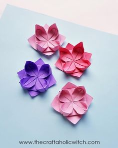 three origami flowers sitting on top of a blue surface