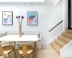 a white table and some chairs in a room with pictures on the wall above it