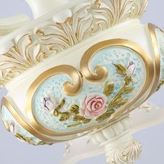 a white and gold vase with flowers on it's sides is hanging from the ceiling