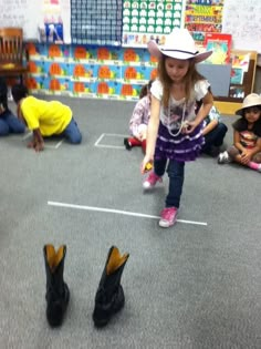 a group of children sitting on the floor in front of black shoes and wearing hats