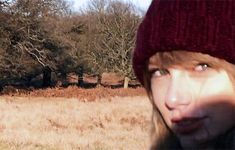 a young man wearing a red hat and making a face in the middle of a field