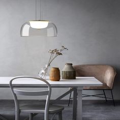 a white table with two vases sitting on top of it next to a chair