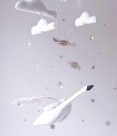 a white swan is flying in the sky with feathers and stars hanging from it's sides