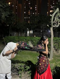 a man and woman standing next to each other in front of a tree at night