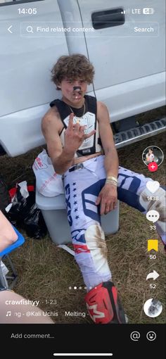 a man sitting on top of a bucket next to a white truck and holding a cell phone