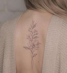 a woman's back shoulder with a flower tattoo on the left side of her neck