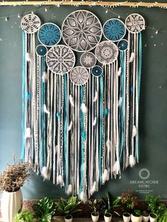 a blue and white dream catcher hanging on the wall next to potted planters