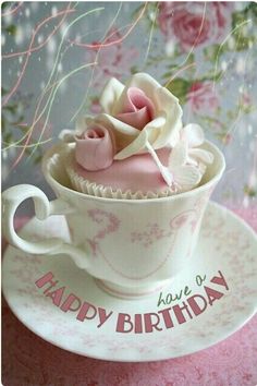 a cupcake in a teacup on a saucer with the words happy birthday