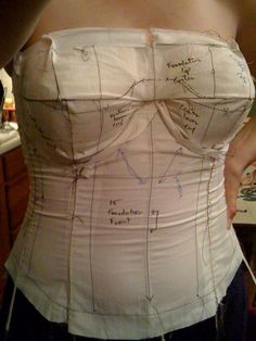 a woman is wearing a white corset with writing on it's back