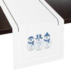 three snowmen on a white table runner