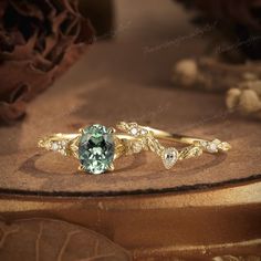 an engagement ring with a green and white stone in the center, on top of a piece of wood