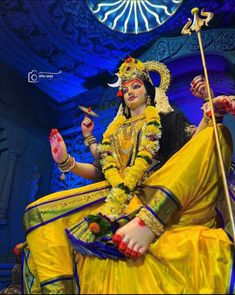 a woman dressed in yellow sitting on top of a statue