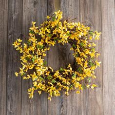 a wreath with yellow flowers hanging on a wooden wall