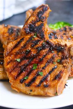 two grilled meats on a white plate with broccoli in the background