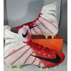 a pair of white and red soccer cleats sitting on top of a box