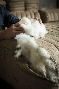 a person holding cotton in their hands on a couch with the fabric removed from it