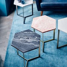 two tables with marble tops on them in a living room area, one is white and the other is blue