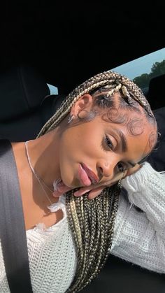 a woman sitting in the back seat of a car with braids on her head