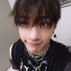 a young man with dark hair wearing a black t - shirt and silver chain necklace