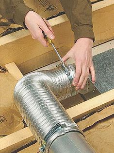 a person using a tool to cut through the metal pipe on top of some wood