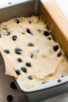 a pan filled with batter and blueberries on top of a table