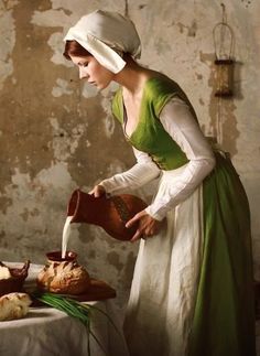 a woman in an old fashion dress is pouring water from a jug