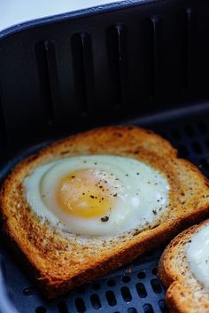 two pieces of bread with an egg in the middle on top of them, sitting on a grill