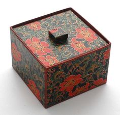 a decorative box with a black lid on a white surface