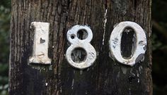 the numbers are written in white paint on a wooden post with trees in the background