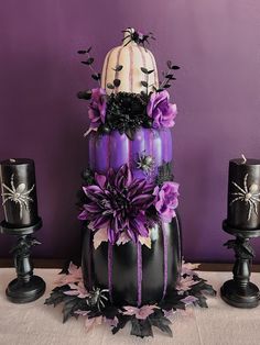 a three tiered cake decorated with purple flowers and black candles on a tablecloth