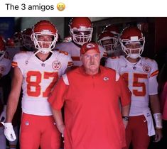 an old man standing in front of a group of football players wearing red and white uniforms