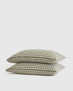 two pillows sitting next to each other on top of a white surface with a black and white checkered pattern